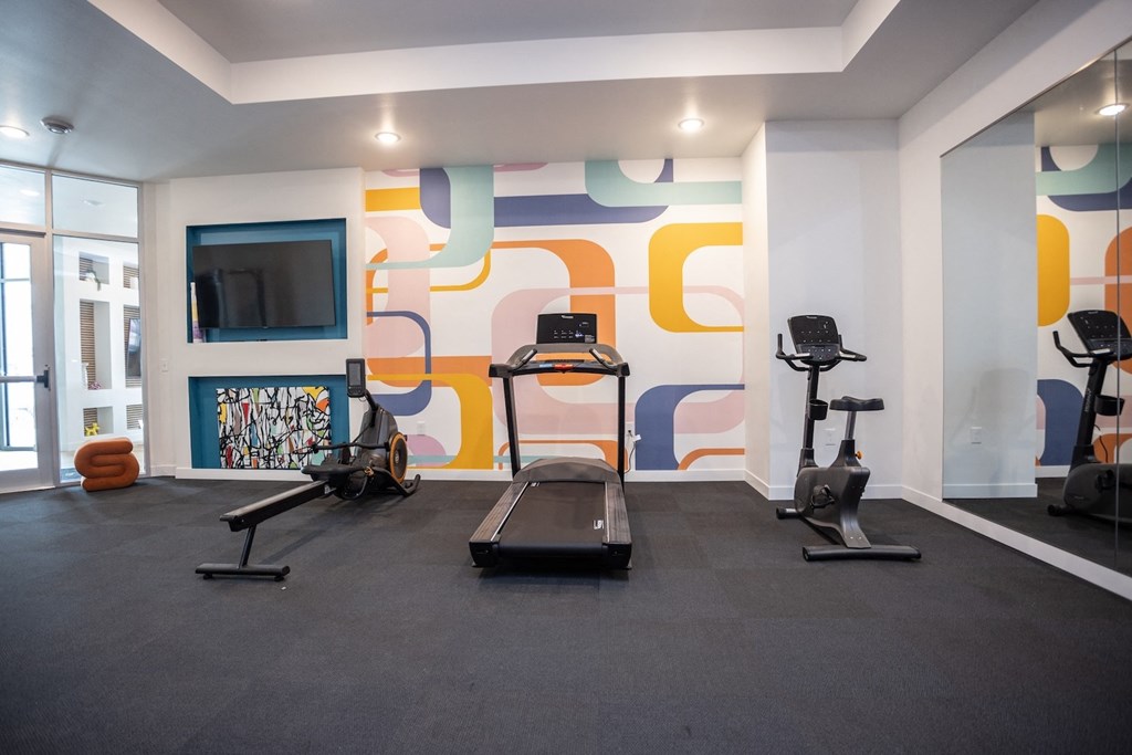 a workout room with treadmills and a tv in a building
