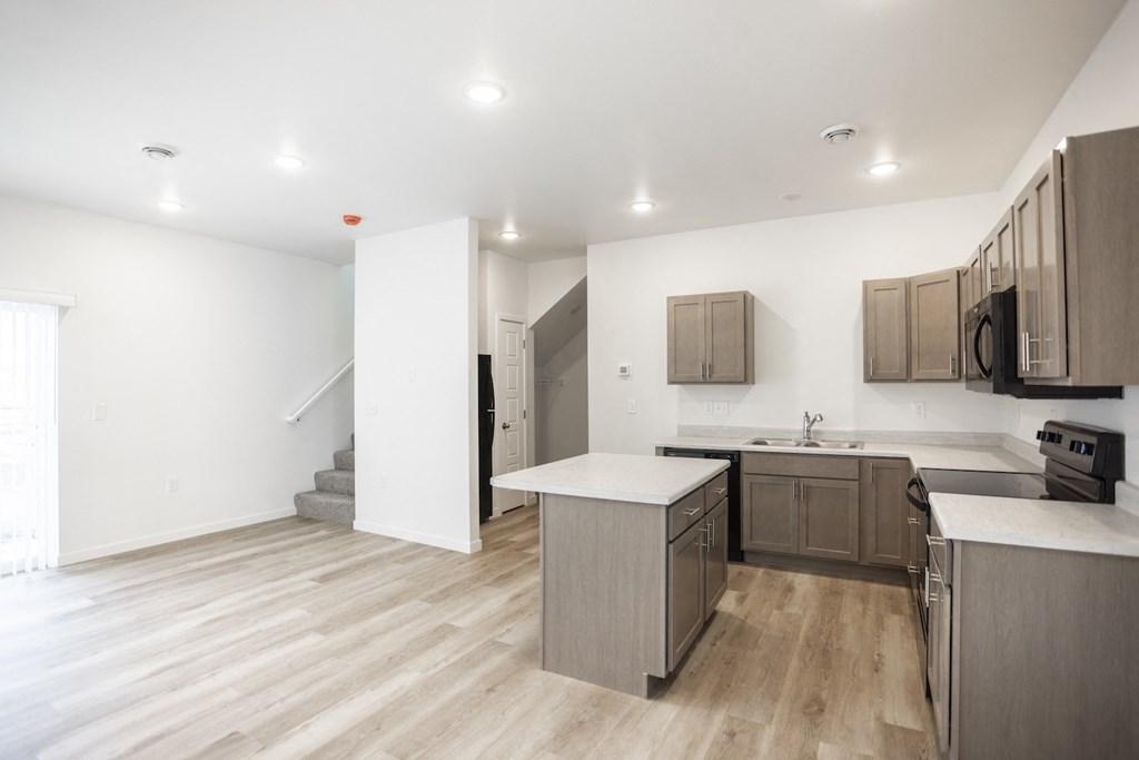 an open kitchen and living room with wood flooring and a staircase