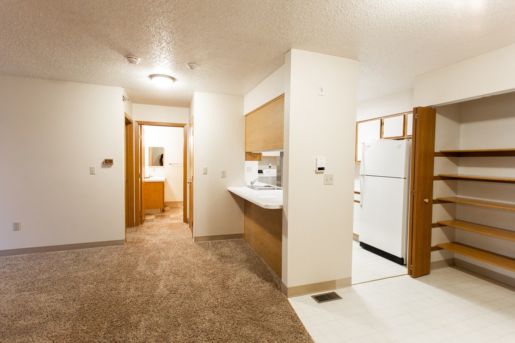 a kitchen and a living room with a white refrigerator and a sink
