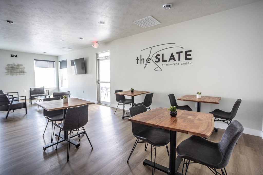 the slate common room with tables and chairs and a logo on the wall