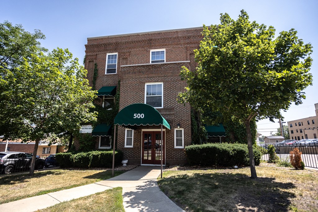 an apartment building with a green awning in front of a sidewalk
