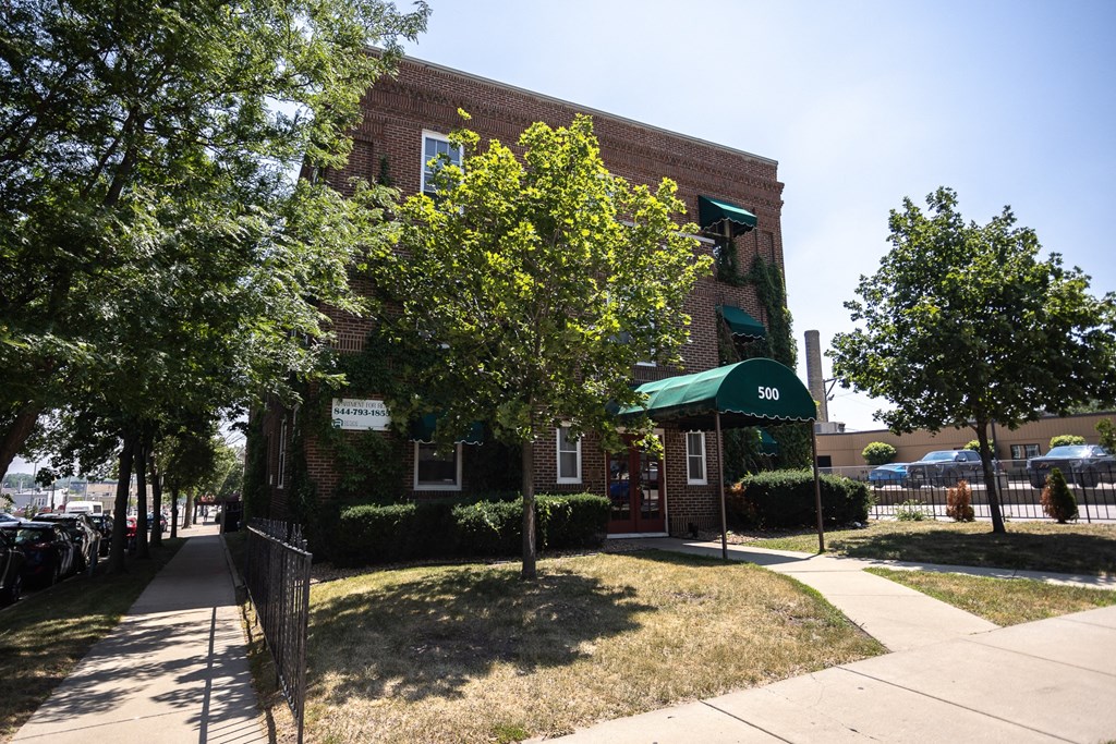 a brick building with a green awning and a tree in front