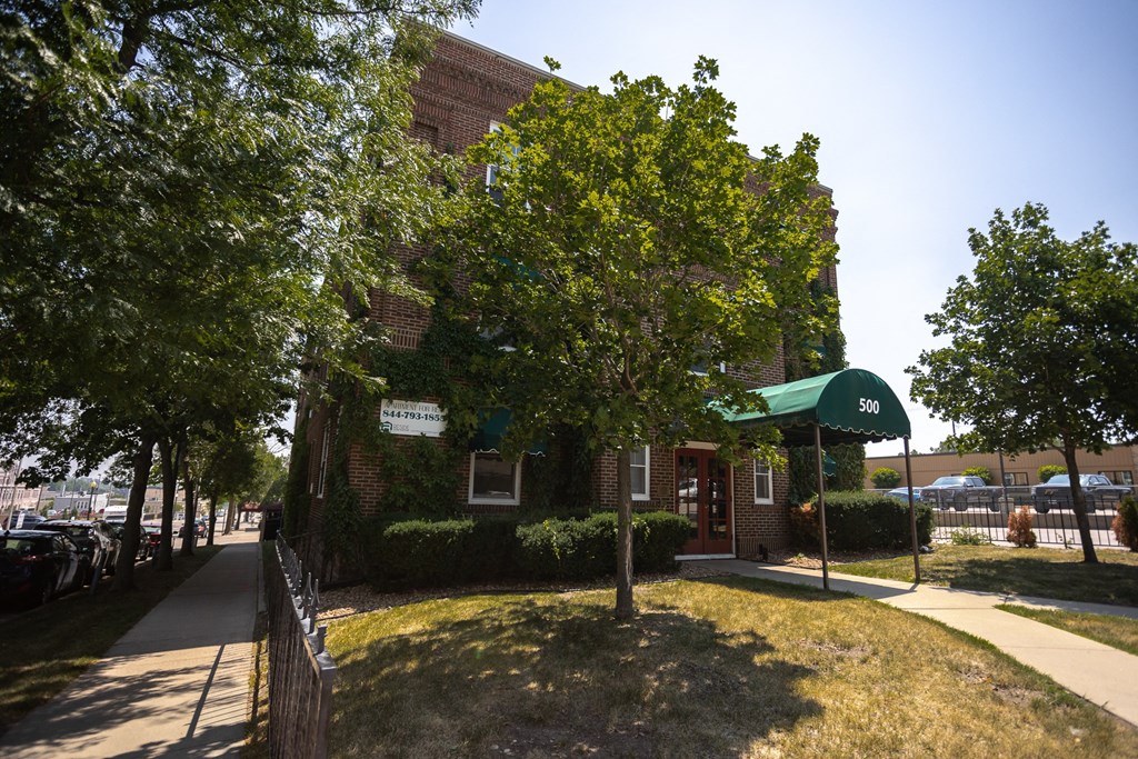 an old brick building with a green awning and a tree in the front