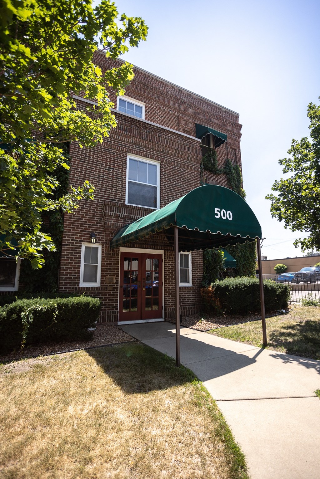 a brick building with a green awning in front of a sidewalk