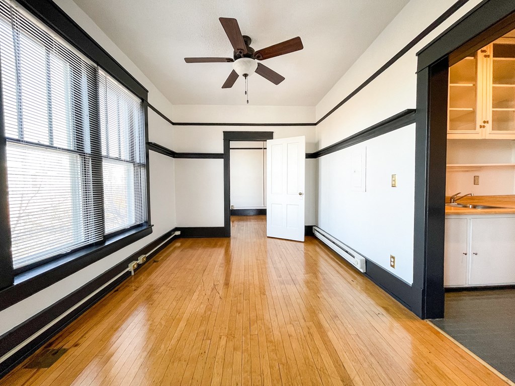 an empty living room with wood floors and a ceiling fan