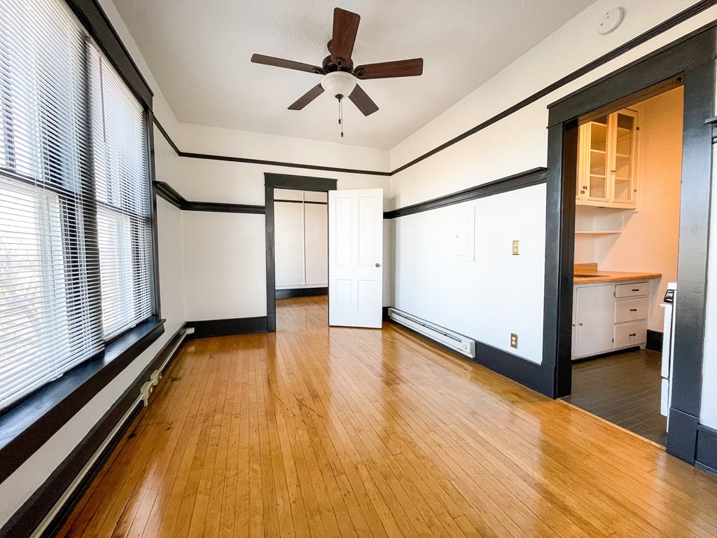 an empty living room with wood floors and a ceiling fan