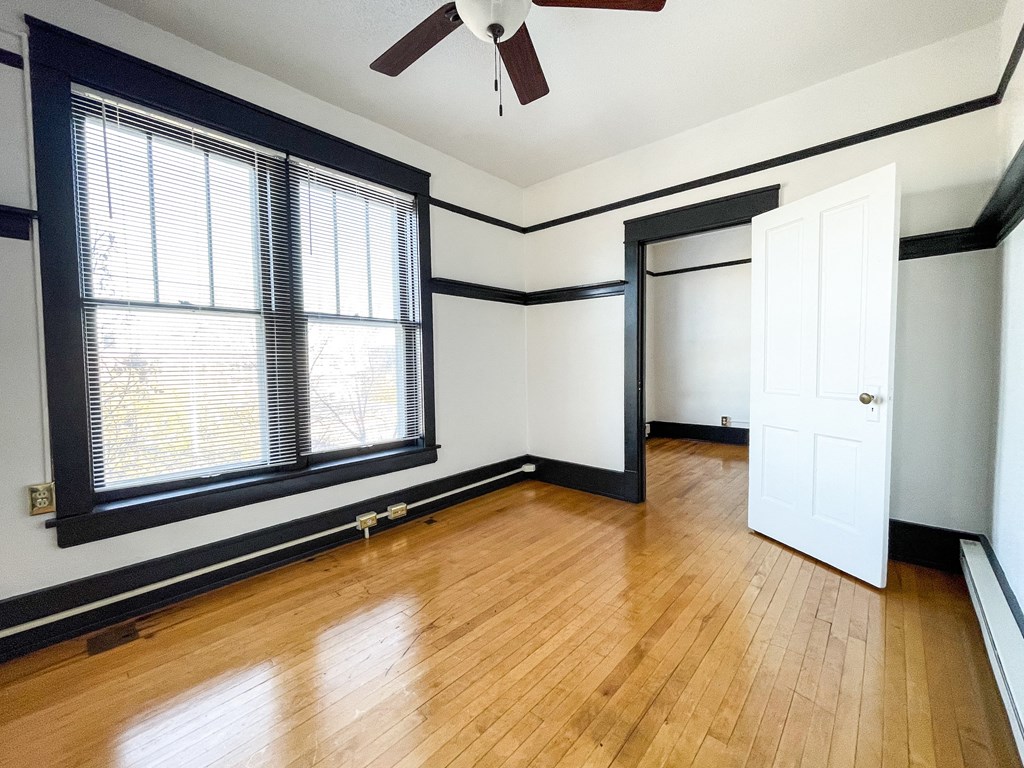an empty living room with wood floors and a ceiling fan