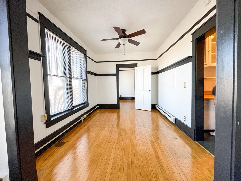 an empty living room with wood floors and a ceiling fan