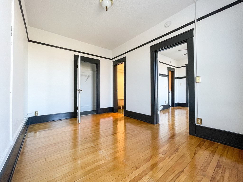 an empty living room with wood floors and white walls