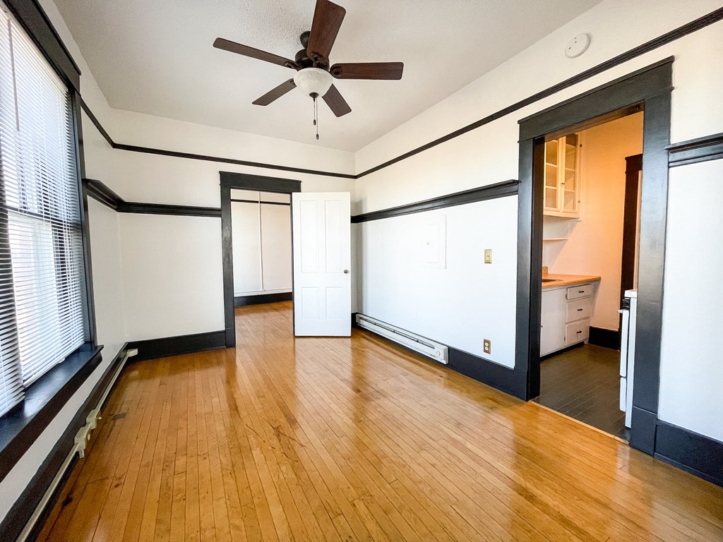 an empty living room with wood floors and a ceiling fan