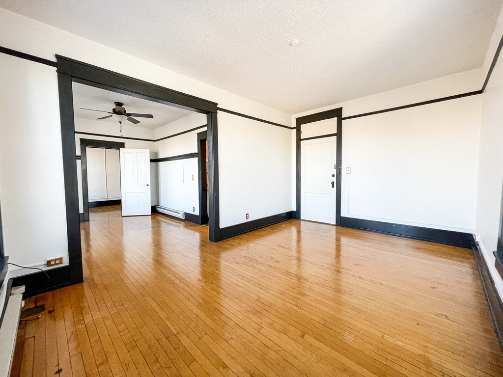 an empty living room with wood floors and white walls