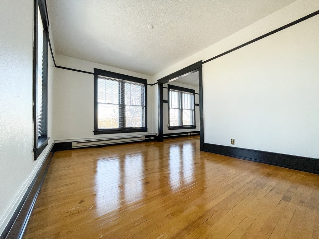 the living room of an empty house with wood floors and windows