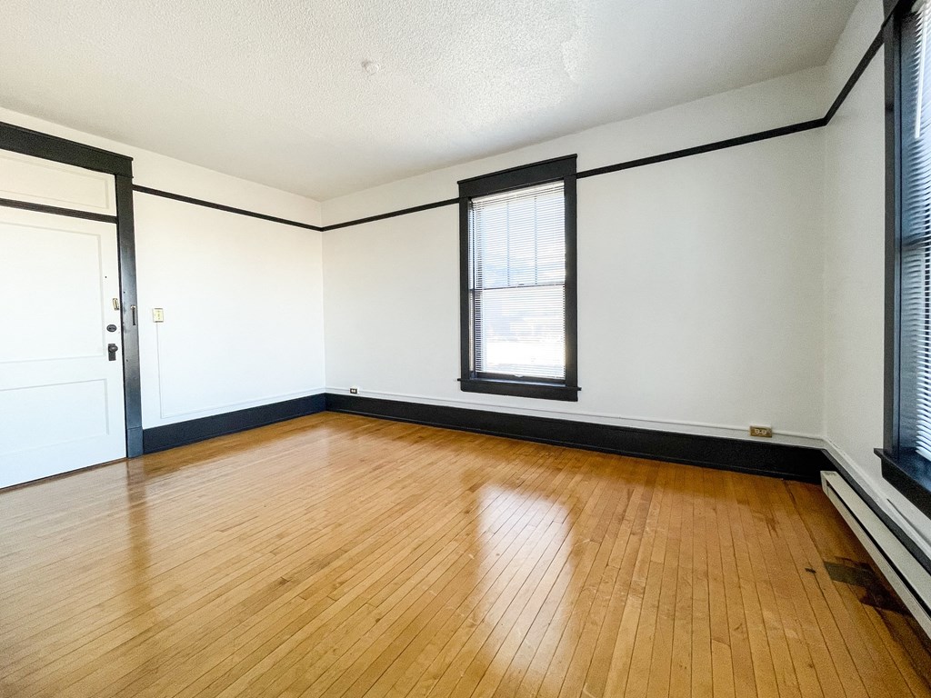 an empty living room with wood floors and white walls