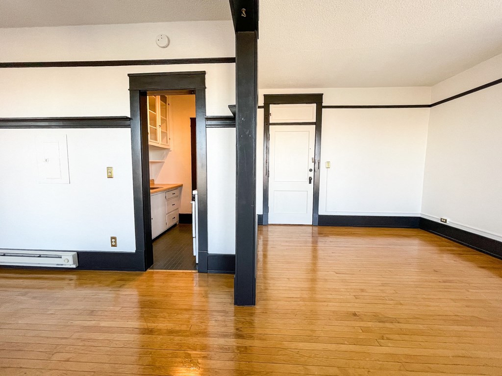 an empty living room with a hard wood floor and white walls