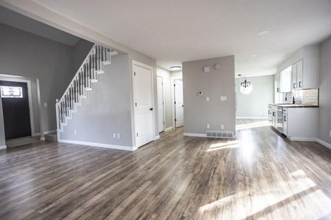 A large empty room with wooden floors and a staircase.