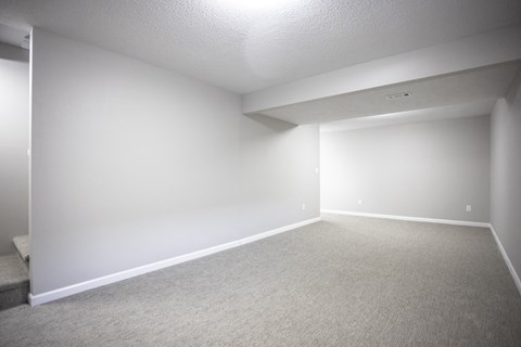 A spacious room with carpeted floor and white walls.