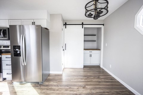A modern kitchen with a stainless steel refrigerator and wooden flooring.