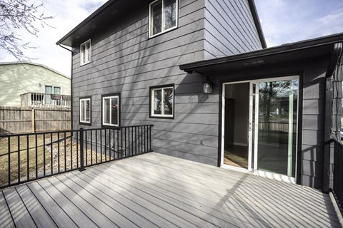 A grey house with a black fence and a glass door.