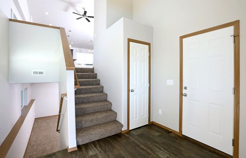 the entryway of a house with stairs and a white door