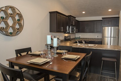 a kitchen and dining area with a wooden table and a stainless steel refrigerator