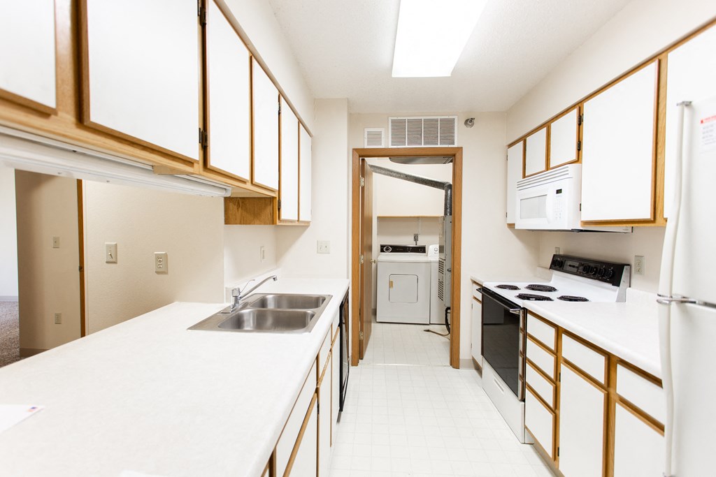a kitchen with white counter tops and a sink and a refrigerator