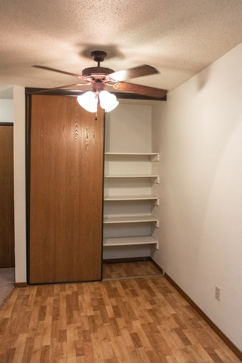 an empty room with a closet and a ceiling fan