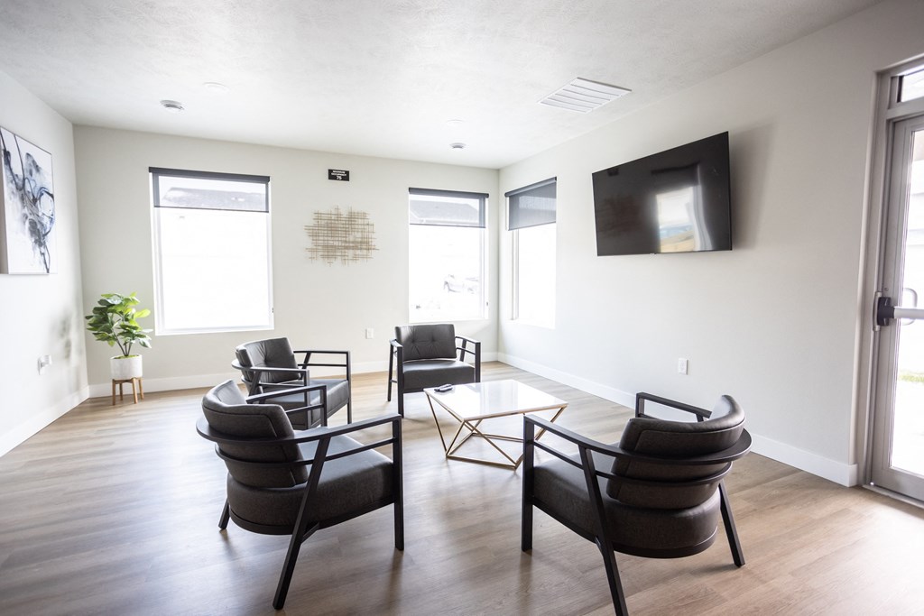 a living room with chairs and a tv on the wall