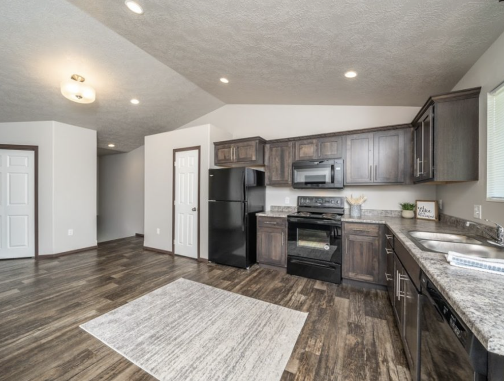 an empty kitchen with black appliances and wooden cabinets