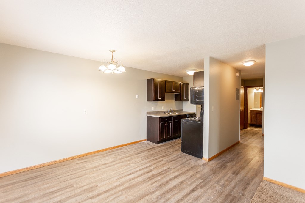 an empty living room and kitchen with a wood floor and white walls