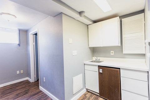 an empty kitchen with white cabinets and a door to a hallway