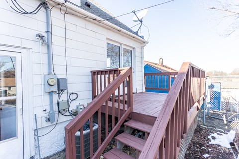 the deck of a house with wooden stairs and a blue fence
