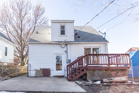 the front of a white house with a porch and a deck