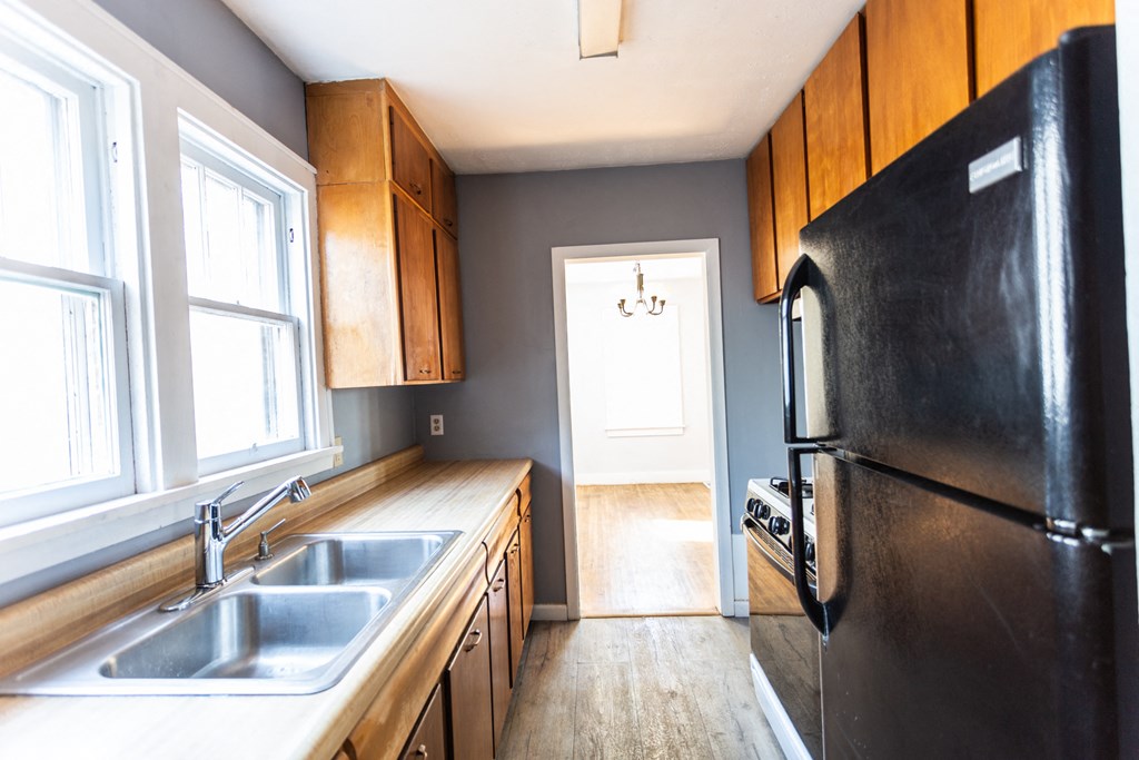 a kitchen with wooden cabinets and a black refrigerator and sink