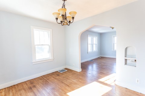 an empty room with a hard wood floor and a chandelier