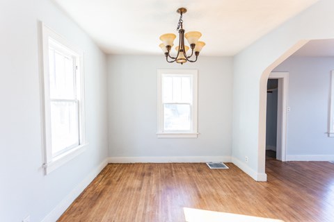 an empty room with a wood floor and a chandelier
