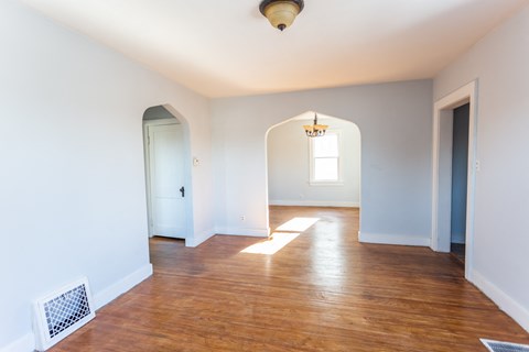an empty living room with a hard wood floor and blue walls