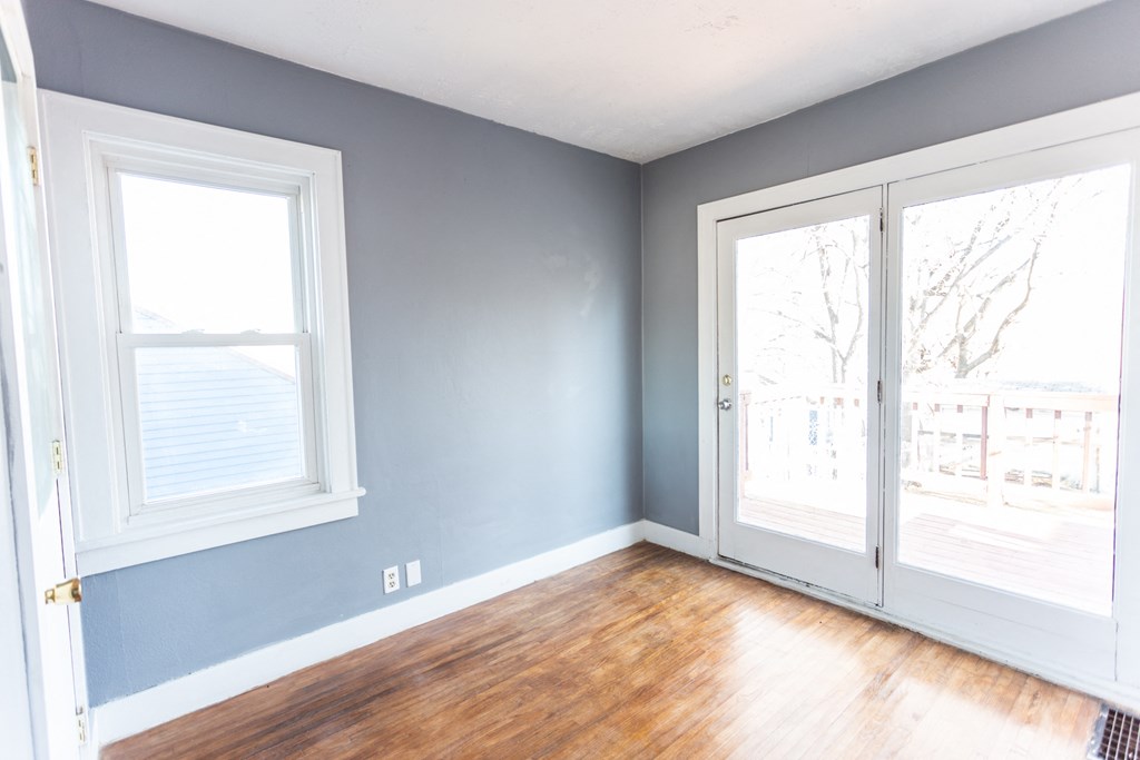an empty room with two doors and a wood floor