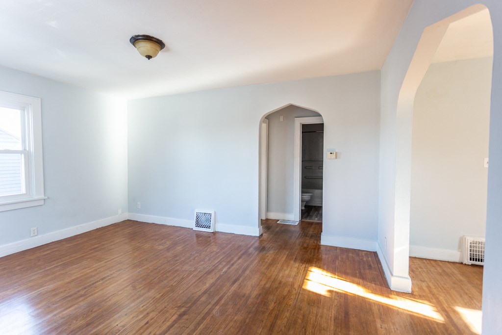 an empty living room with a hard wood floor and white walls