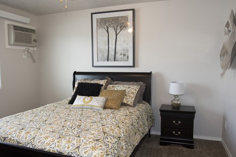 a bedroom with a bed and a night stand and a picture on the wall