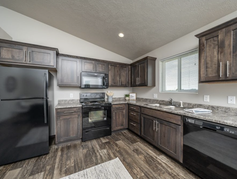 the kitchen of a home with dark cabinets and stainless steel appliances