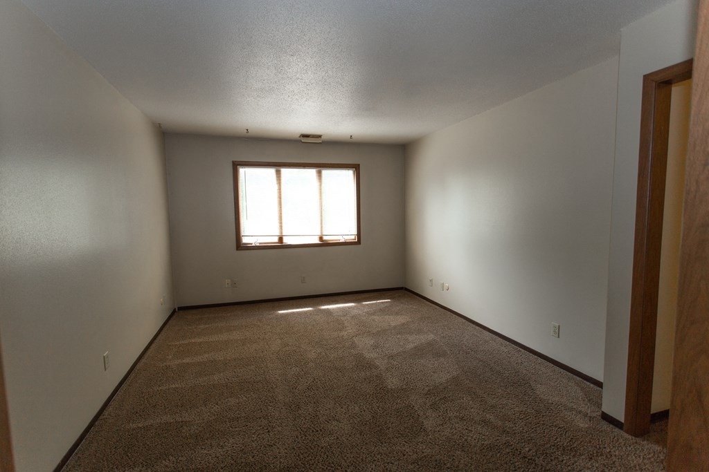 a empty living room with a window in the corner