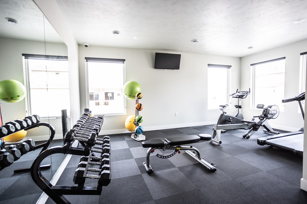 a gym with weights and other exercise equipment in a room with windows