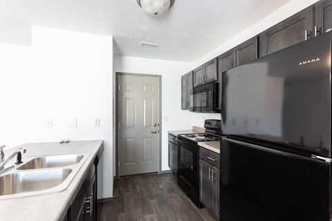 a kitchen with black appliances and a sink and a refrigerator
