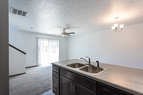 an empty kitchen with a sink and a ceiling fan