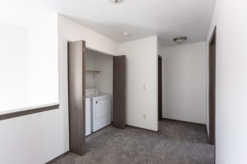 an empty room with a laundry room and a door to a closet