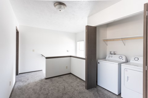 an empty laundry room with washer and dryer and white walls and flooring