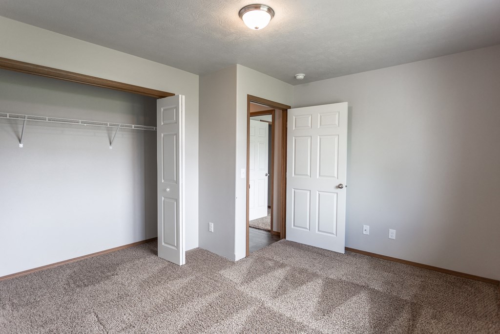 an empty bedroom with a closet and a door to a bathroom