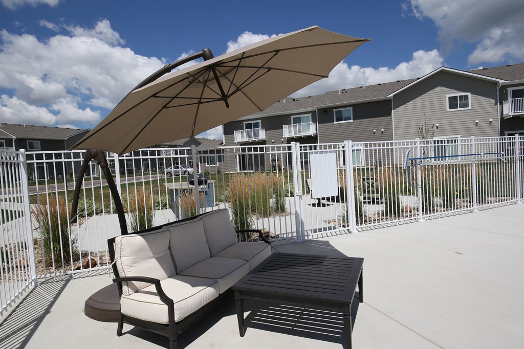 A patio with a couch and umbrella.