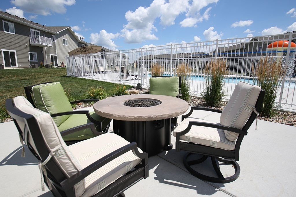 A patio with a table and chairs overlooking a pool.