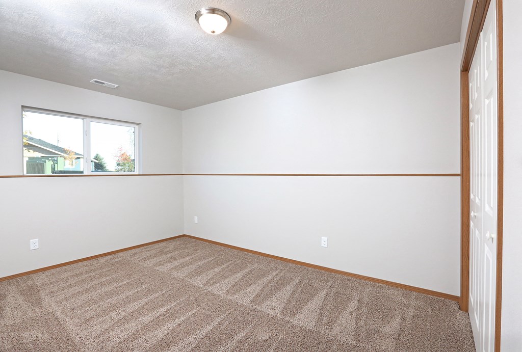 an empty living room with carpet and a window